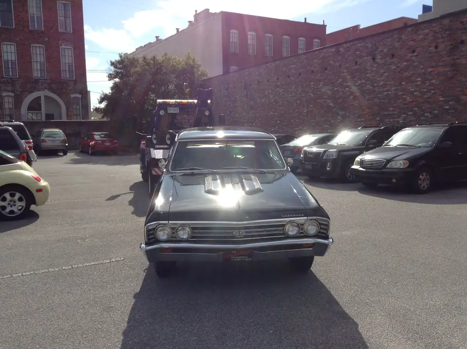 Black Chevy Chevelle hooked to Joey's wrecker in a downtown parking lot